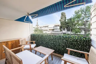 a patio with tables and chairs and a green hedge at Renovated apt with Parking & Terrace - Palm Beach in Cannes