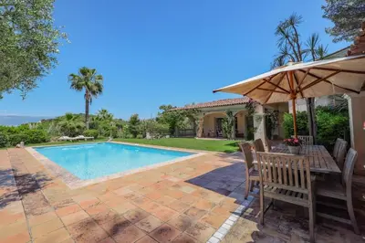 a patio with a table and an umbrella next to a swimming pool at REF 1849 - Cannes - Villa Provencal Style to rent in Le Cannet