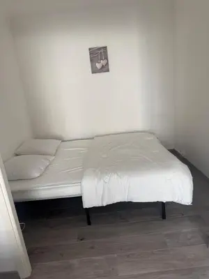 a bed in a room with a white wall at Appartement cosy in Cannes