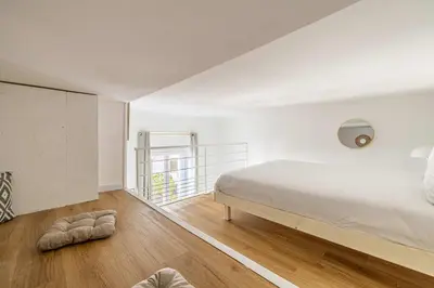 a bedroom with a large white bed and wooden floors at LE PETIT PALAIS avec mezzanine de charme au cœur de Cannes in Cannes
