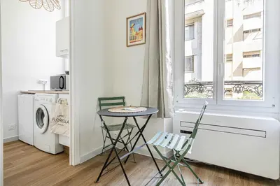 a small table and two chairs in a kitchen with a window at LE PETIT PALAIS avec mezzanine de charme au cœur de Cannes in Cannes
