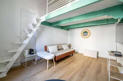 a bedroom with a bed and a staircase in a room at LE PETIT PALAIS avec mezzanine de charme au cœur de Cannes in Cannes