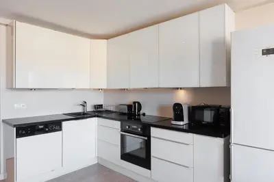 a white kitchen with white cabinets and a microwave at Appartement lumineux Cannes proche mer in Cannes
