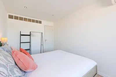 a white bedroom with a white bed and orange pillows at Appartement lumineux Cannes proche mer in Cannes