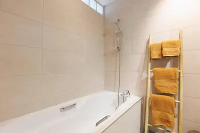a bathroom with a tub and a shower with yellow towels at Appartement lumineux Cannes proche mer in Cannes