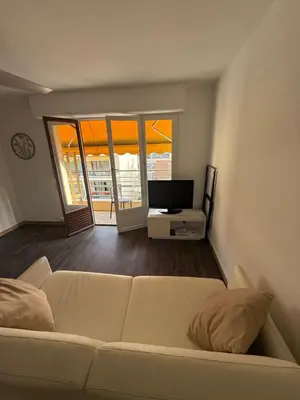 a living room with a white couch and a television at St Paul Cannes in Cannes