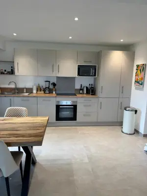 a kitchen with white cabinets and a wooden table at Kazanou in Cannes