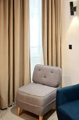 a chair sitting in front of a window with curtains at Alma Apart Residence in Cannes