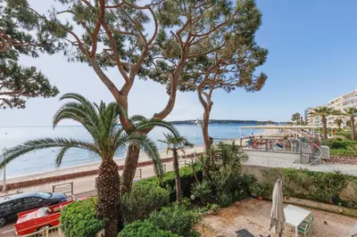 a view of the beach from a resort with palm trees at Fettolina YourHostHelper in Cannes