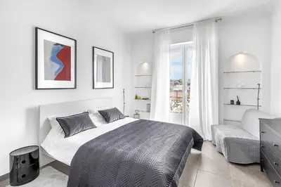 a white bedroom with a bed and a chair at Croisette 65 apartment-Miramar residence in Cannes