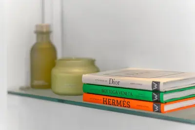 a stack of books sitting on a shelf with a bottle at Croisette 65 apartment-Miramar residence in Cannes