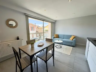 a living room with a table and a blue couch at La Rose d'Or - SCLS Locations in Le Cannet