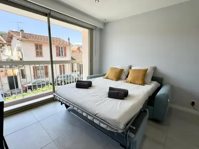 a bed in a room with a large window at La Rose d'Or - SCLS Locations in Le Cannet