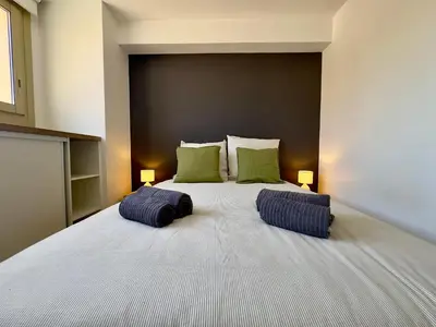 a bedroom with a large bed with two green pillows at La Rose d'Or - SCLS Locations in Le Cannet