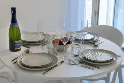 a white table with plates and glasses and a bottle of wine at 2-Br Apartment Terrace Cannes City Centre in Cannes