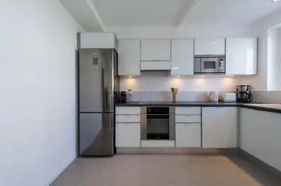 a kitchen with white cabinets and a stainless steel refrigerator at 2-Br Apartment Terrace Cannes City Centre in Cannes