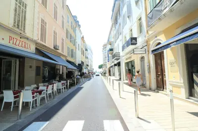 a woman walking down a street with tables and chairs at Lumineux 2 chambres, CARRE D'OR-COEUR DE CANNES A2B196 in Cannes