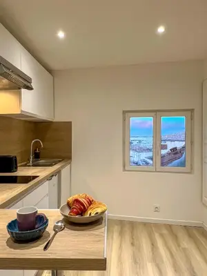 a kitchen with a table and two windows at Studio Vue Mer au coeur du Suquet in Cannes