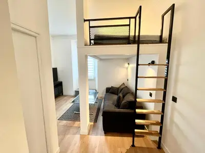 a living room with a couch and a loft bed at Studio Neuf Clim 4p - Cannes in Cannes