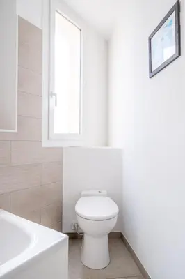 a white bathroom with a toilet and a window at LE MADRID avec balcon proche Croisette plages et Palais des Festivals in Cannes