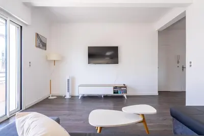 a white living room with a couch and a tv at LE MADRID avec balcon proche Croisette plages et Palais des Festivals in Cannes