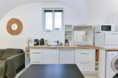 a small kitchen with white cabinets and a couch at L'ESPERANCE Studio joli petit situé dans le Suquet, proche des commerces, Palais et plages in Cannes