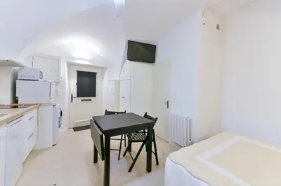 a white kitchen with a black table in a room at L'ESPERANCE Studio joli petit situé dans le Suquet, proche des commerces, Palais et plages in Cannes