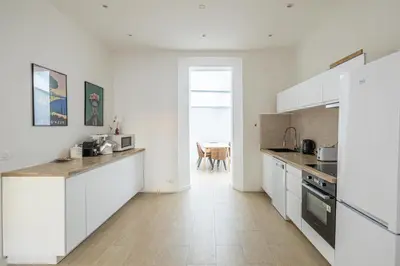 a kitchen with white cabinets and a wooden floor at LE WINDSOR avec extérieur, spacieux et chaleureux pour un plaisir partagé in Cannes