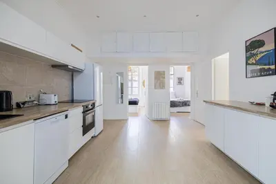 a kitchen with white cabinets and a wooden floor at LE WINDSOR avec extérieur, spacieux et chaleureux pour un plaisir partagé in Cannes