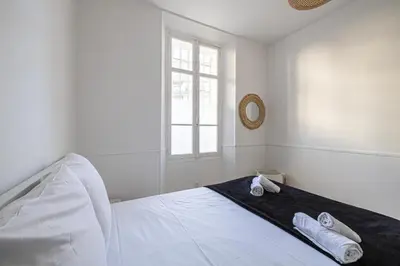 a white bedroom with a bed with towels on it at LE WINDSOR avec extérieur, spacieux et chaleureux pour un plaisir partagé in Cannes