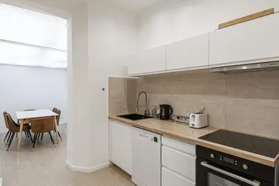 a kitchen with white cabinets and a table at LE WINDSOR avec extérieur, spacieux et chaleureux pour un plaisir partagé in Cannes