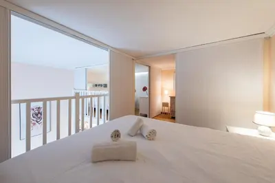 a bedroom with a white bed and a large window at LE RIMBAUD splendide duplex dans le Suquet, près des plages et du Palais des Festivals in Cannes