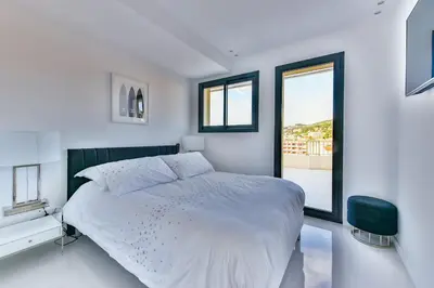 a white bedroom with a large bed and a window at L'HORIZON avec somptueuse terrasse vue mer in Cannes