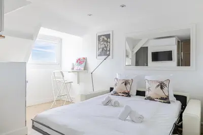 a white bedroom with a bed and a chair at LE VANILLE studio cosy au cœur de la Banane in Cannes