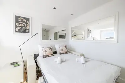 a white bedroom with a bed and a mirror at LE VANILLE studio cosy au cœur de la Banane in Cannes