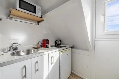 a white kitchen with a sink and a microwave at LE VANILLE studio cosy au cœur de la Banane in Cannes