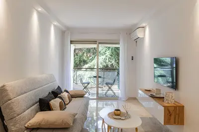 a living room with a couch and a table at LE CENTER avec joli balcon et parking pour un plaisant séjour in Cannes
