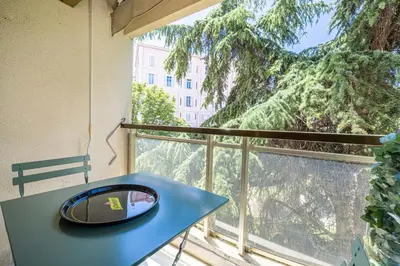 a blue table on a balcony with a view of a tree at LE CENTER avec joli balcon et parking pour un plaisant séjour in Cannes