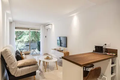 a living room with a couch and a table at LE CENTER avec joli balcon et parking pour un plaisant séjour in Cannes