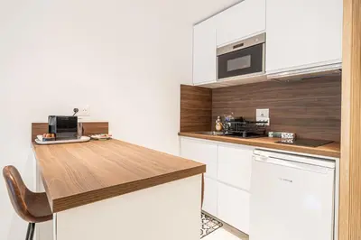 a kitchen with white cabinets and a wooden counter top at LE CENTER avec joli balcon et parking pour un plaisant séjour in Cannes