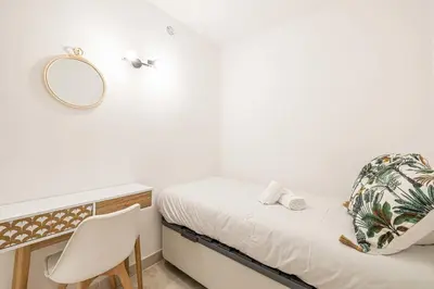 a small bedroom with a bed and a mirror at LE CENTER avec joli balcon et parking pour un plaisant séjour in Cannes