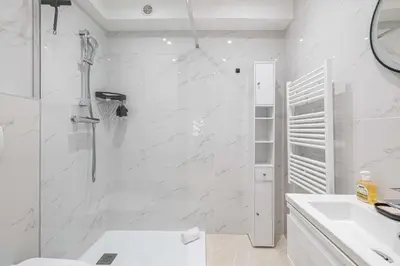 a white bathroom with a shower and a sink at LE CENTER avec joli balcon et parking pour un plaisant séjour in Cannes