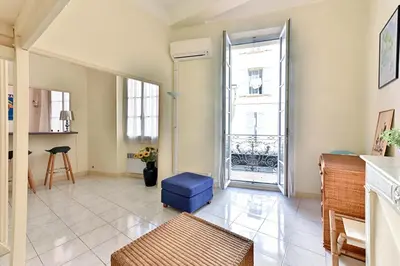 a living room with a blue ottoman and a window at LE RÉTRO studio avec mezzanine en plein centre in Cannes