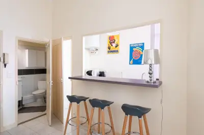 a kitchen with three bar stools and a sink at LE RÉTRO studio avec mezzanine en plein centre in Cannes