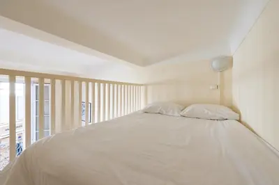 a bedroom with a white bed with two pillows at LE RÉTRO studio avec mezzanine en plein centre in Cannes