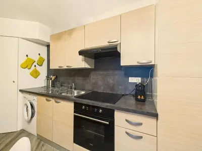 a kitchen with wooden cabinets and a stove top oven at LE PALME D'OR splendide studio cocon près de la Croisette, du Palais et des plages in Cannes