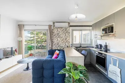 a living room with a blue couch and a kitchen at LA PALMERAIE joyeux studio avec balcon, à deux pas de la Banane in Cannes