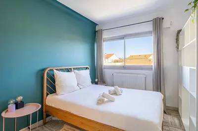 a bedroom with a bed with a blue wall and a window at LA PALMERAIE joyeux studio avec balcon, à deux pas de la Banane in Cannes
