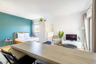 a room with a table and a bedroom with a bed at LA PALMERAIE joyeux studio avec balcon, à deux pas de la Banane in Cannes