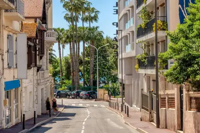 two people walking down a street with palm trees at Duplex centre de Cannes - terrasse, sunset & pool in Cannes